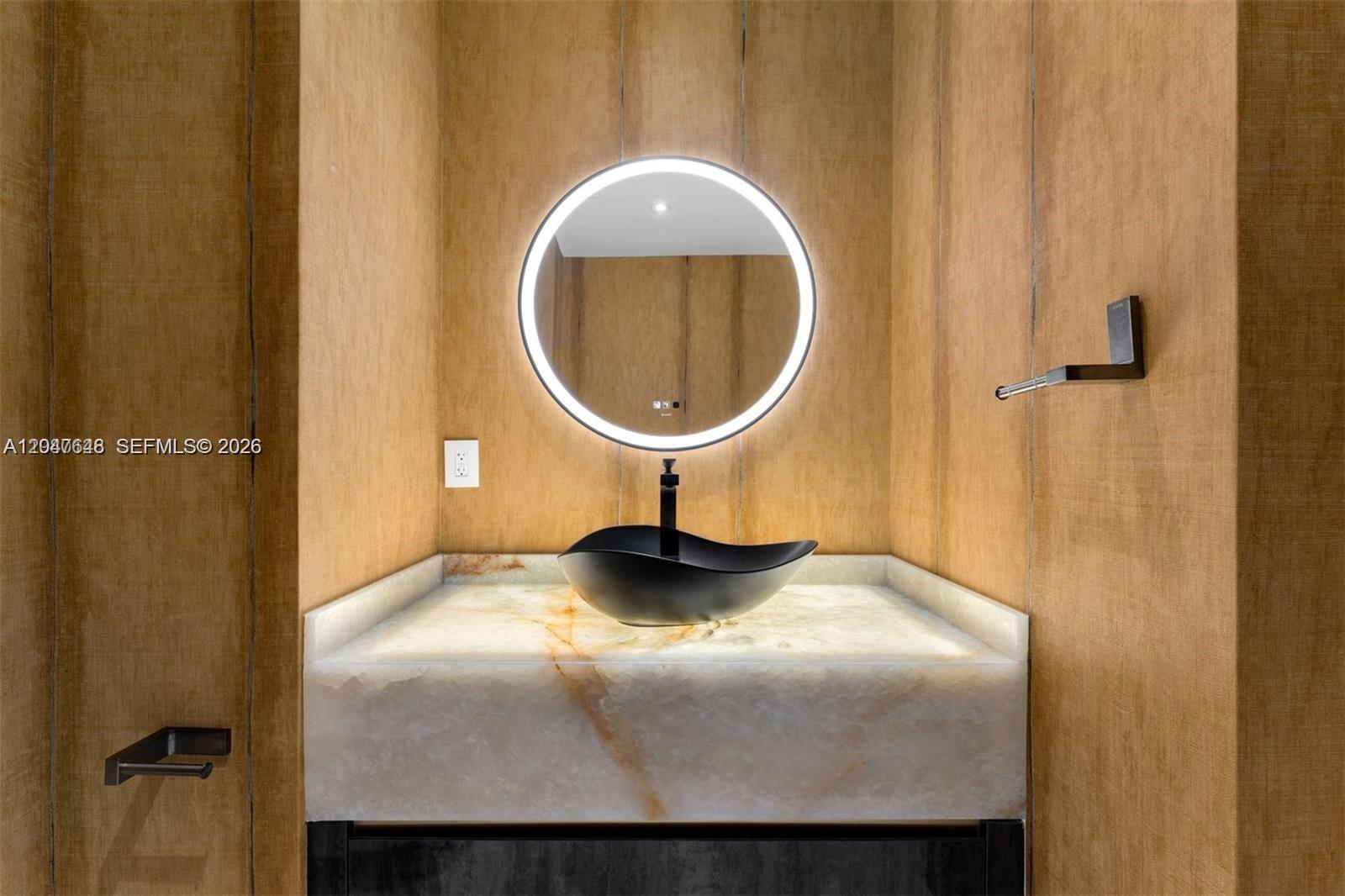 A modern powder room features a backlit stone vanity, a black vessel sink, and a mirror — 900 Biscayne Blvd # 4202, Miami FL 33132, MIAMI, FL