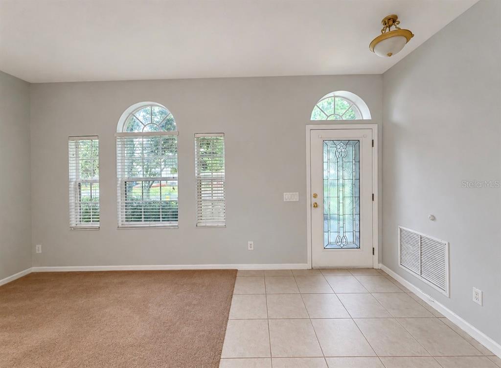A room with beige carpet, tiled flooring, a front door with a window, and arched windows — 9630 BATON ROUGE LANE, LAND O LAKES, FL