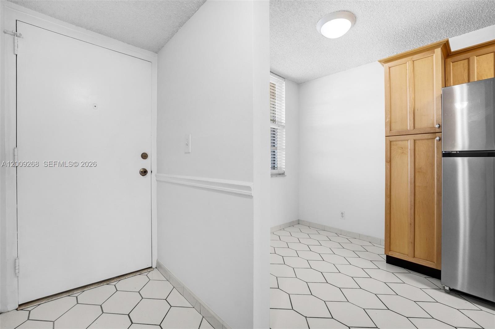 A white door opens into a kitchen area featuring light wood cabinets and tiled flooring — 250 Jacaranda Dr # 508, Plantation FL 33324, PLANTATION, FL