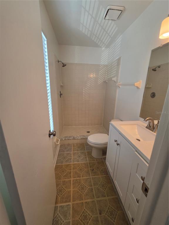 A small bathroom featuring a walk-in shower, a white vanity, and patterned tile flooring — 11038 REGENCY COMMONS COURT, ORLANDO, FL