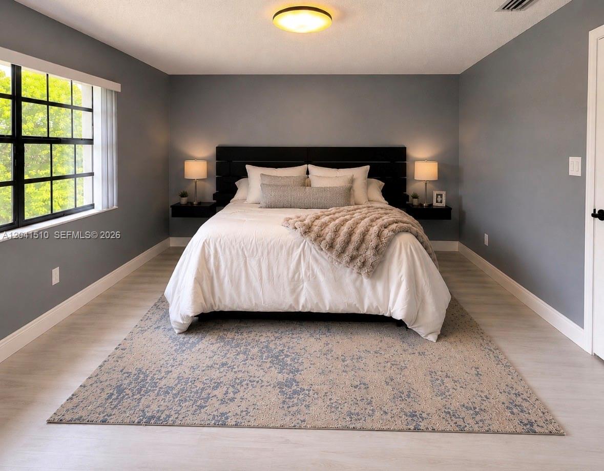 A bedroom features gray walls, a black headboard, floating nightstands, and a patterned area rug — 1120 NE 209th Ter, Miami FL 33179, MIAMI, FL