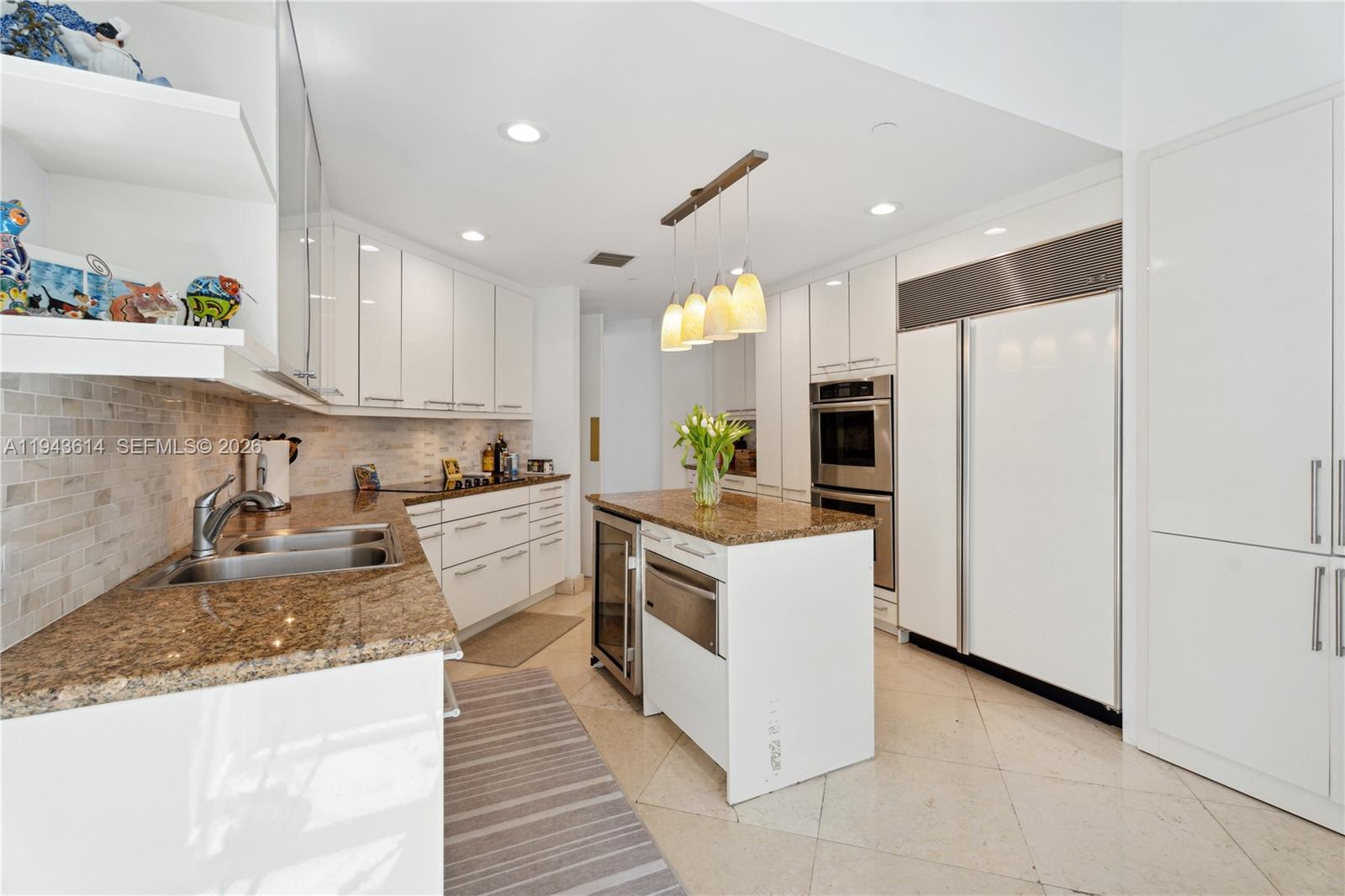A modern kitchen features white cabinetry, granite countertops, a central island, and stainless steel appliances — 10225 Collins Ave # 904, Bal Harbour FL 33154, BAL HARBOUR, FL