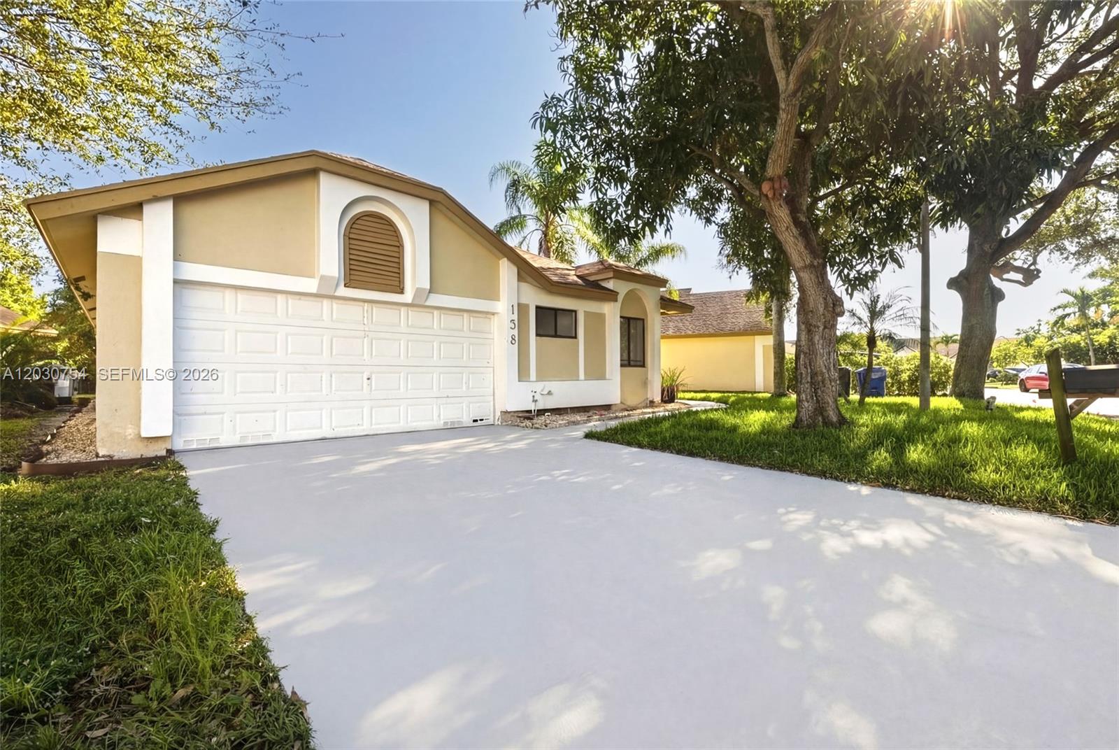 A single-story house features a white garage door, tan stucco walls, and a paved driveway — NORTH LAUDERDALE, FL