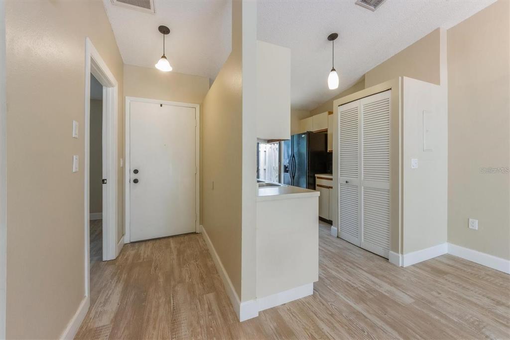An entryway leads to a kitchen with light wood-look flooring and white louvered closet doors — 2903 62ND STREET W UNIT 303, BRADENTON, FL