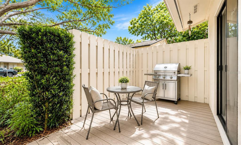 A small patio features a round table, two chairs, a stainless steel grill, and fencing — 2903 62ND STREET W UNIT 303, BRADENTON, FL