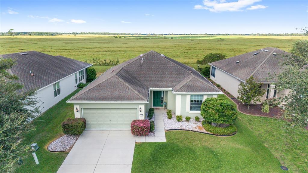 An aerial view of a single-story house with a garage and a large grassy field — 7346 SW 101ST COURT, OCALA, FL