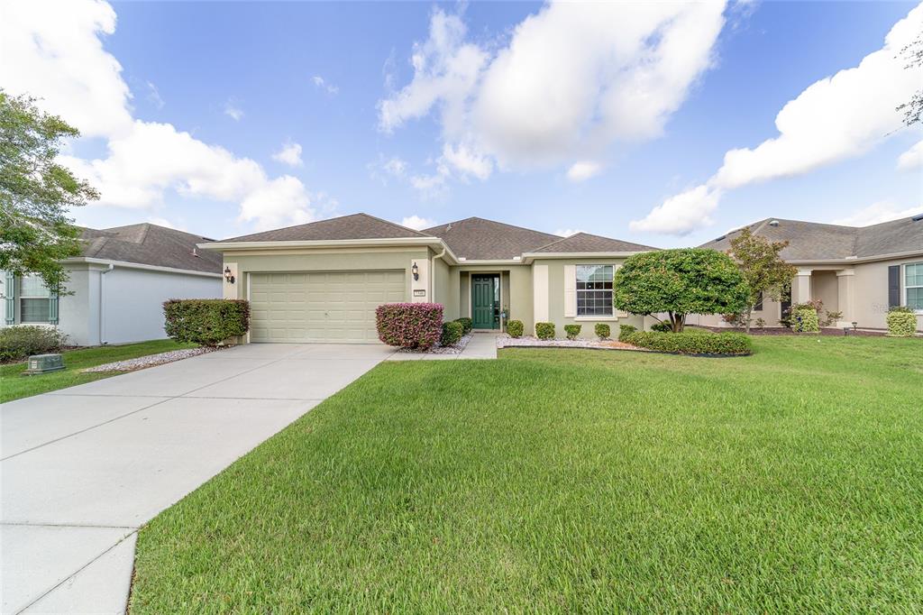 A single-story house with a green exterior, a two-car garage, and a manicured lawn — 7346 SW 101ST COURT, OCALA, FL