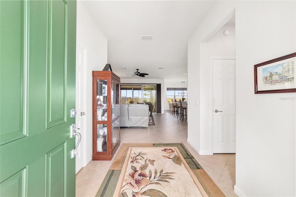 A view from an open green front door into a tiled foyer and living area — 7346 SW 101ST COURT, OCALA, FL
