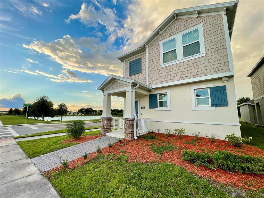 A two-story house with tan siding, blue shutters, and a stone-accented front porch — 1543 CROSS PRAIRIE PARKWAY, KISSIMMEE, FL