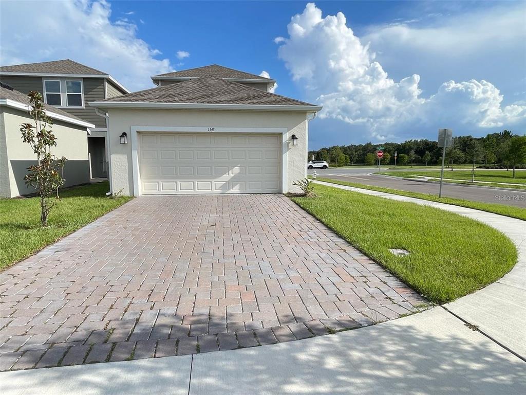 A beige house with a brick paver driveway and a two-car garage — 1543 CROSS PRAIRIE PARKWAY, KISSIMMEE, FL