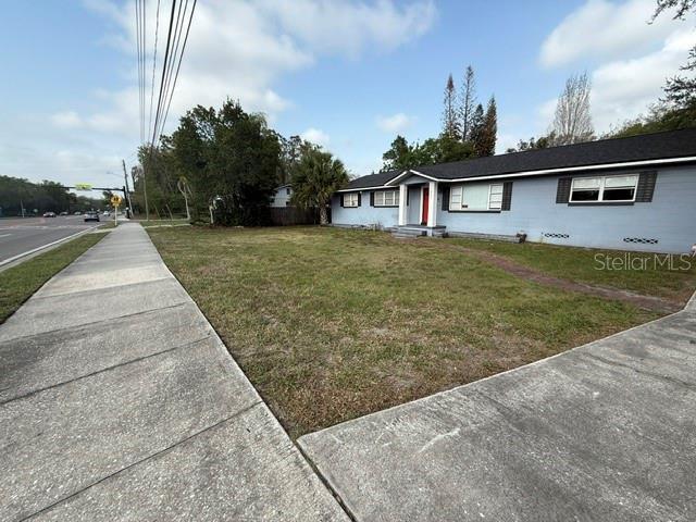 A light blue single-story house sits behind a grassy front yard and a concrete sidewalk — 1825 N DEAN ROAD, ORLANDO, FL