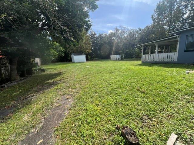 A large, grassy backyard features a small white shed and a house with a porch — 1825 N DEAN ROAD, ORLANDO, FL
