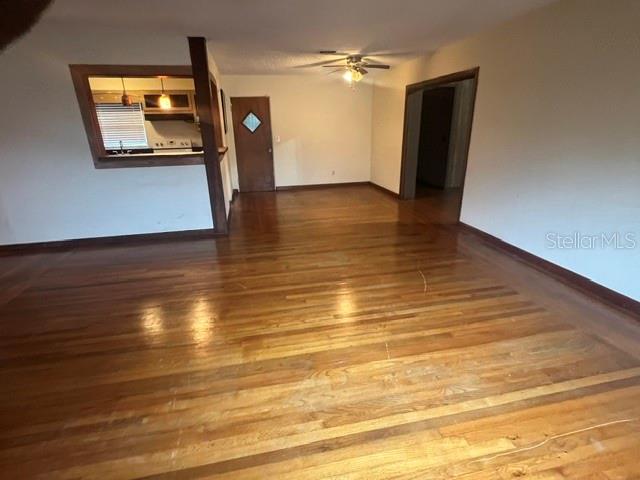 An empty living room features hardwood floors, a ceiling fan, and a kitchen pass-through window — 1825 N DEAN ROAD, ORLANDO, FL