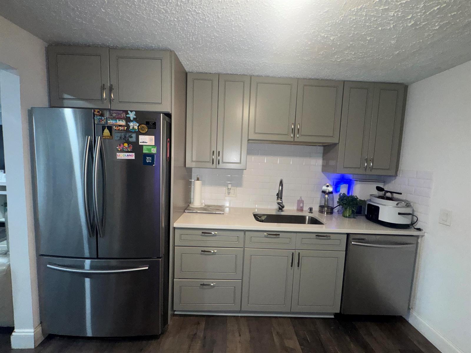 A kitchen features gray shaker cabinets, stainless steel appliances, white countertops, and a subway tile backsplash — 4328 Pine Street, FL 33406, FL