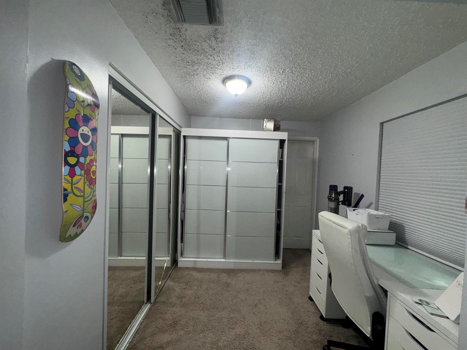 A room with a desk, a large wardrobe, mirrored closet doors, and a decorative skateboard — 4328 Pine Street, FL 33406, FL