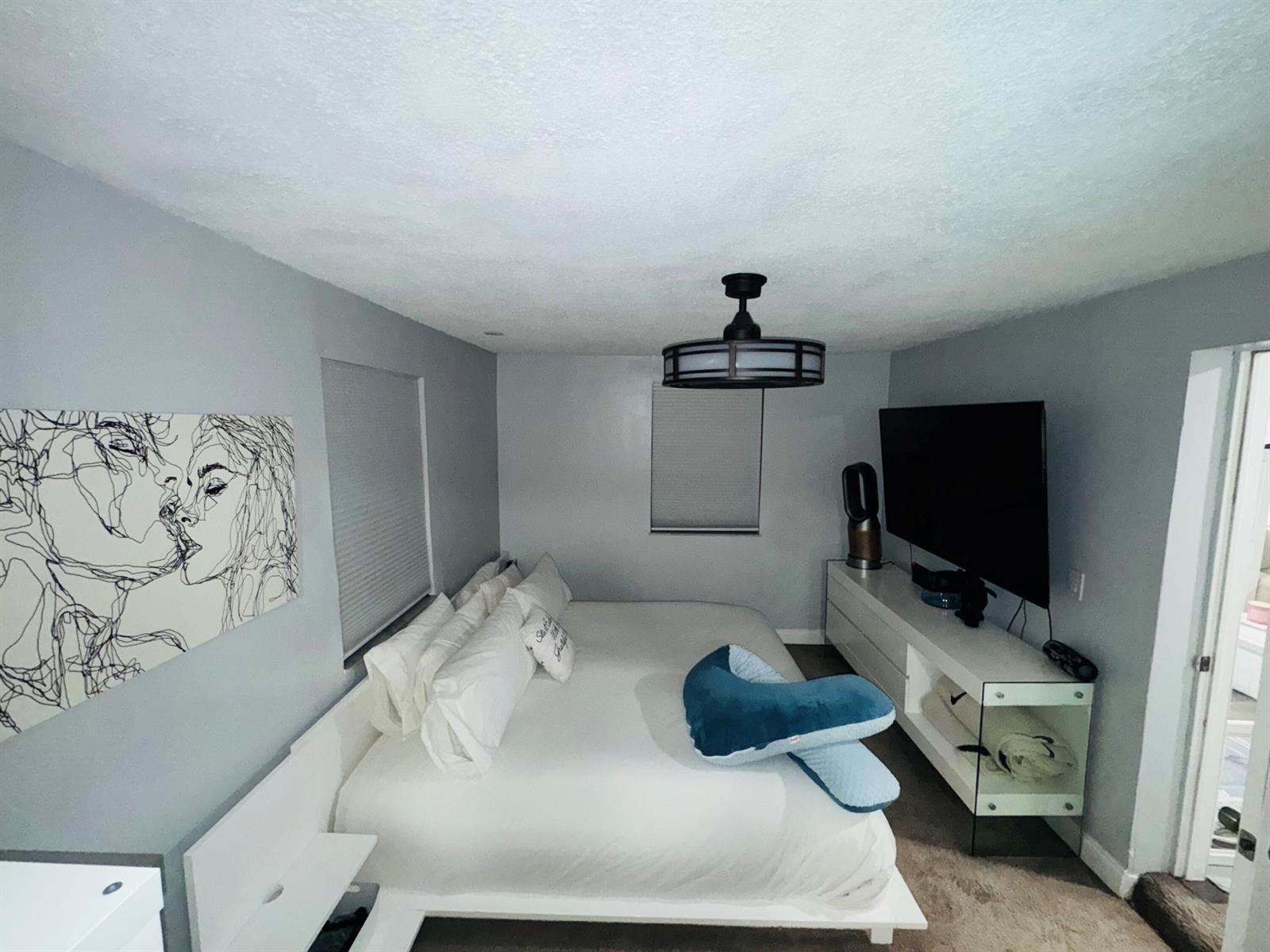 A bedroom features a platform bed, a wall-mounted television, and a modern ceiling fan — 4328 Pine Street, FL 33406, FL