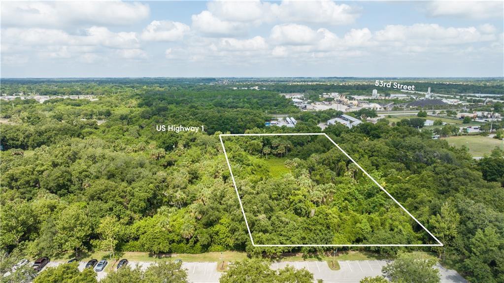 An aerial view shows a rectangular plot of land outlined in white near a parking lot — VERO BEACH, FL