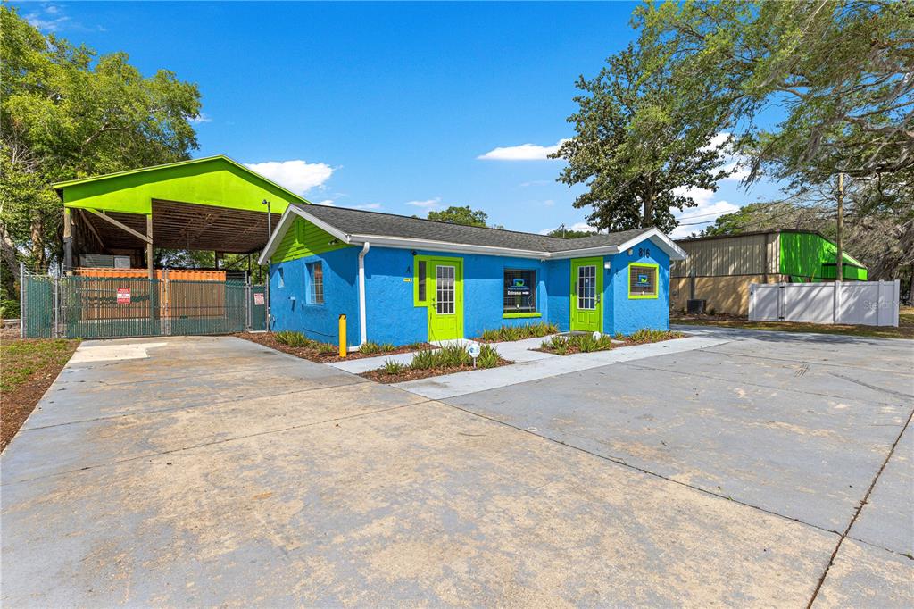 A bright blue commercial building with lime green doors and trim sits on a concrete lot — 816 NW 30TH AVENUE, OCALA, FL