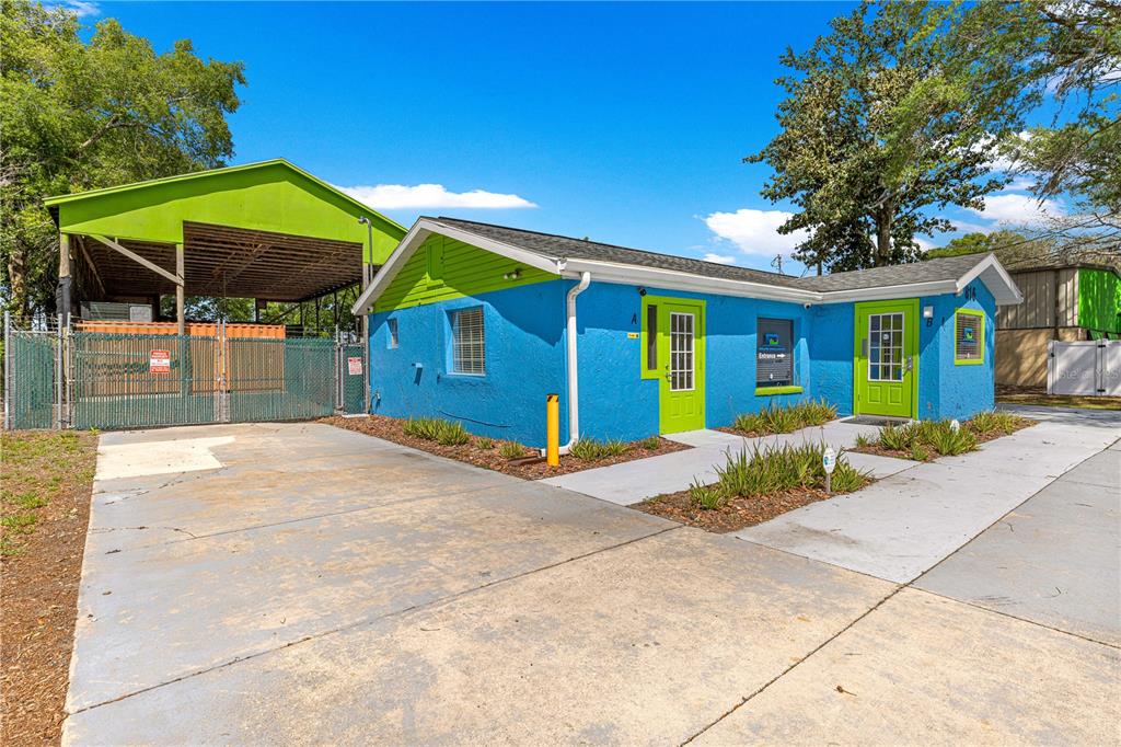 A blue commercial building with lime green doors and trim sits next to a covered structure — 816 NW 30TH AVENUE, OCALA, FL