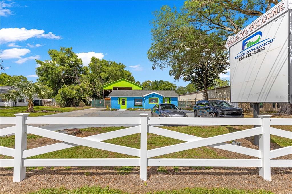 A bright blue commercial building with a green roof sits behind a white fence — 816 NW 30TH AVENUE, OCALA, FL