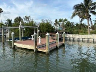 A wooden boat dock with a lift sits on a canal surrounded by tropical vegetation — 14065 N BAYSHORE DRIVE, MADEIRA BEACH, FL