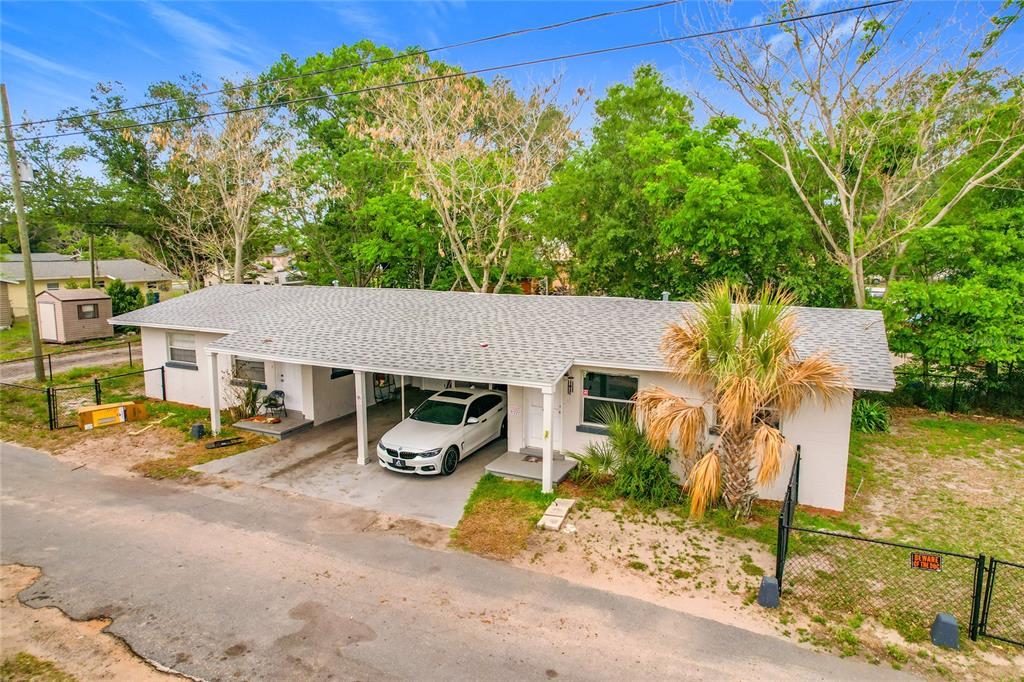 A single-story house with a white exterior, a carport, and a palm tree in front — 627 WASHINGTON AVENUE, LAKE WALES, FL