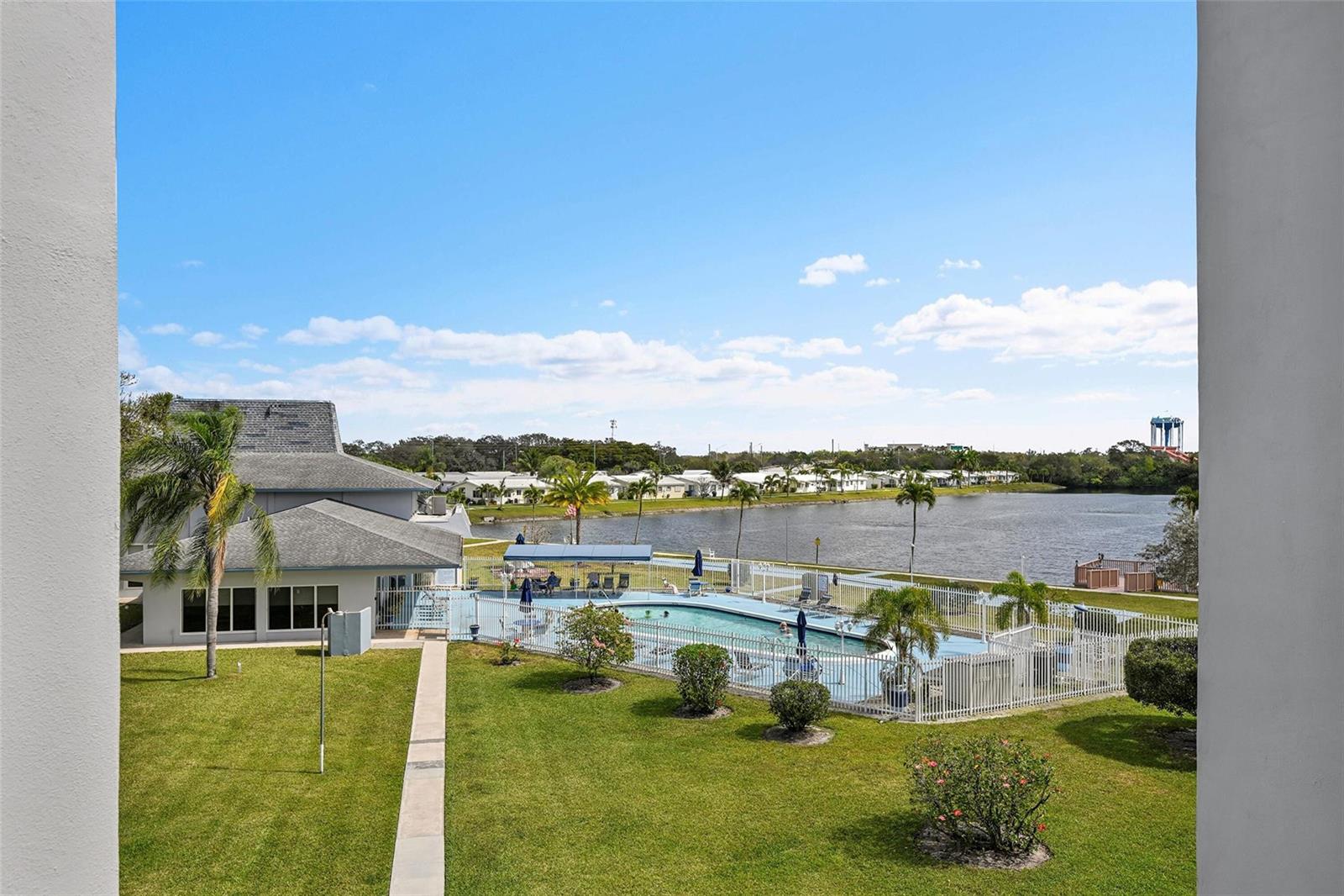 An elevated view shows a swimming pool, lawn, and lake behind a residential building — 2223 Park Lane # 302, Hollywood FL 33021, HOLLYWOOD, FL