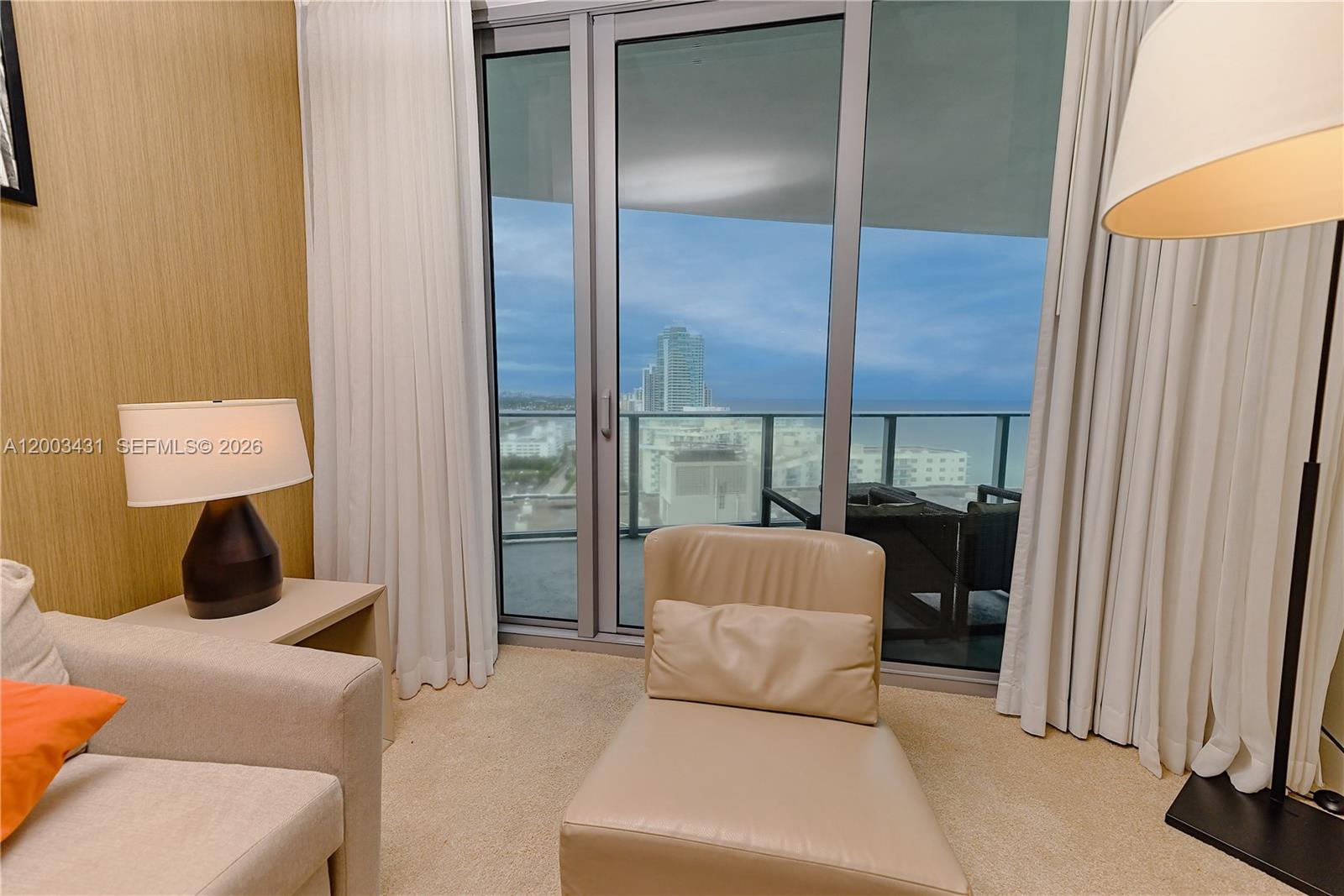A room with a lounge chair, sofa, and floor-to-ceiling windows overlooking the ocean — 4111 S Ocean Dr # 1710, Hollywood FL 33019, HOLLYWOOD, FL