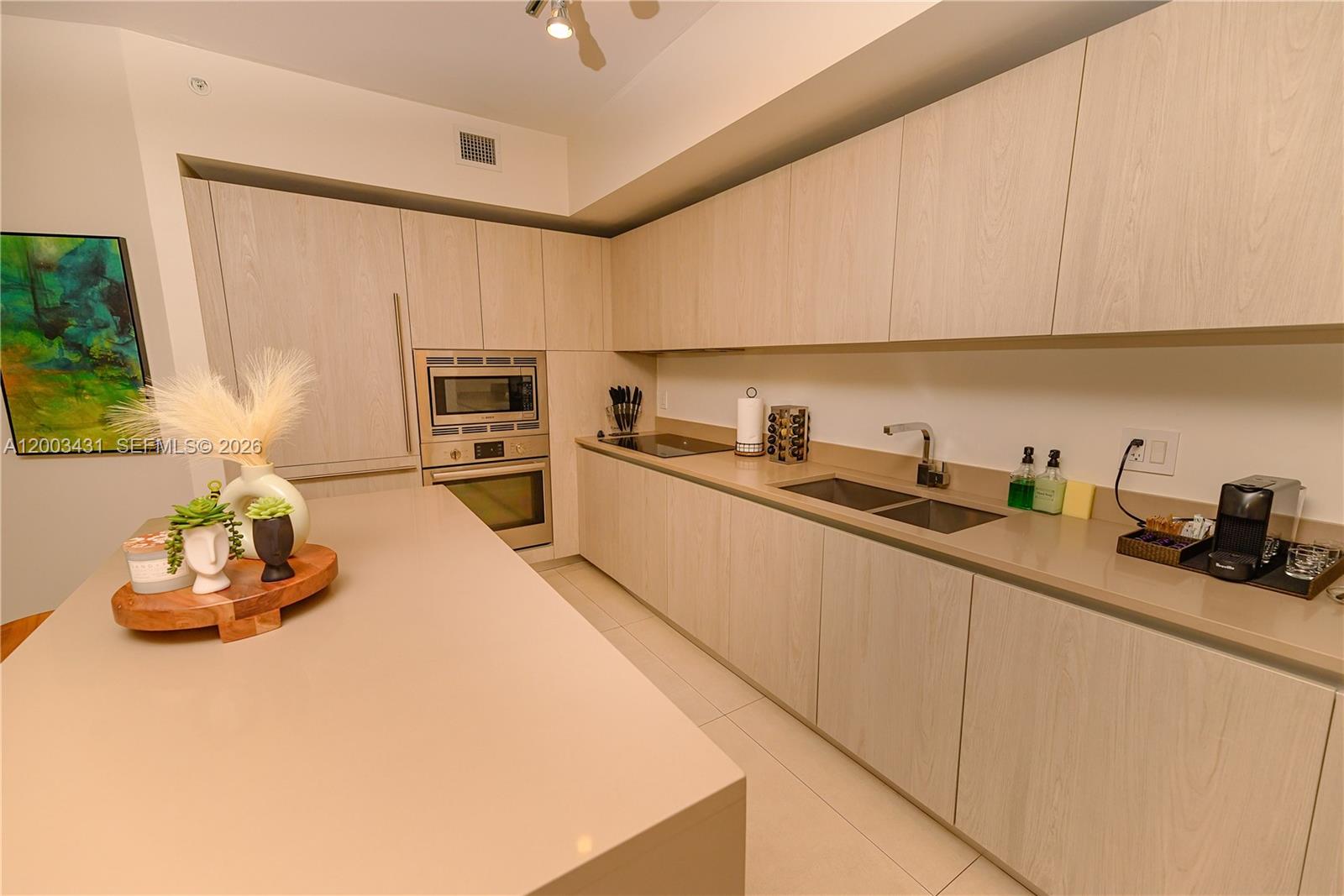 A modern kitchen features light wood cabinetry, a large island, and stainless steel appliances — 4111 S Ocean Dr # 1710, Hollywood FL 33019, HOLLYWOOD, FL