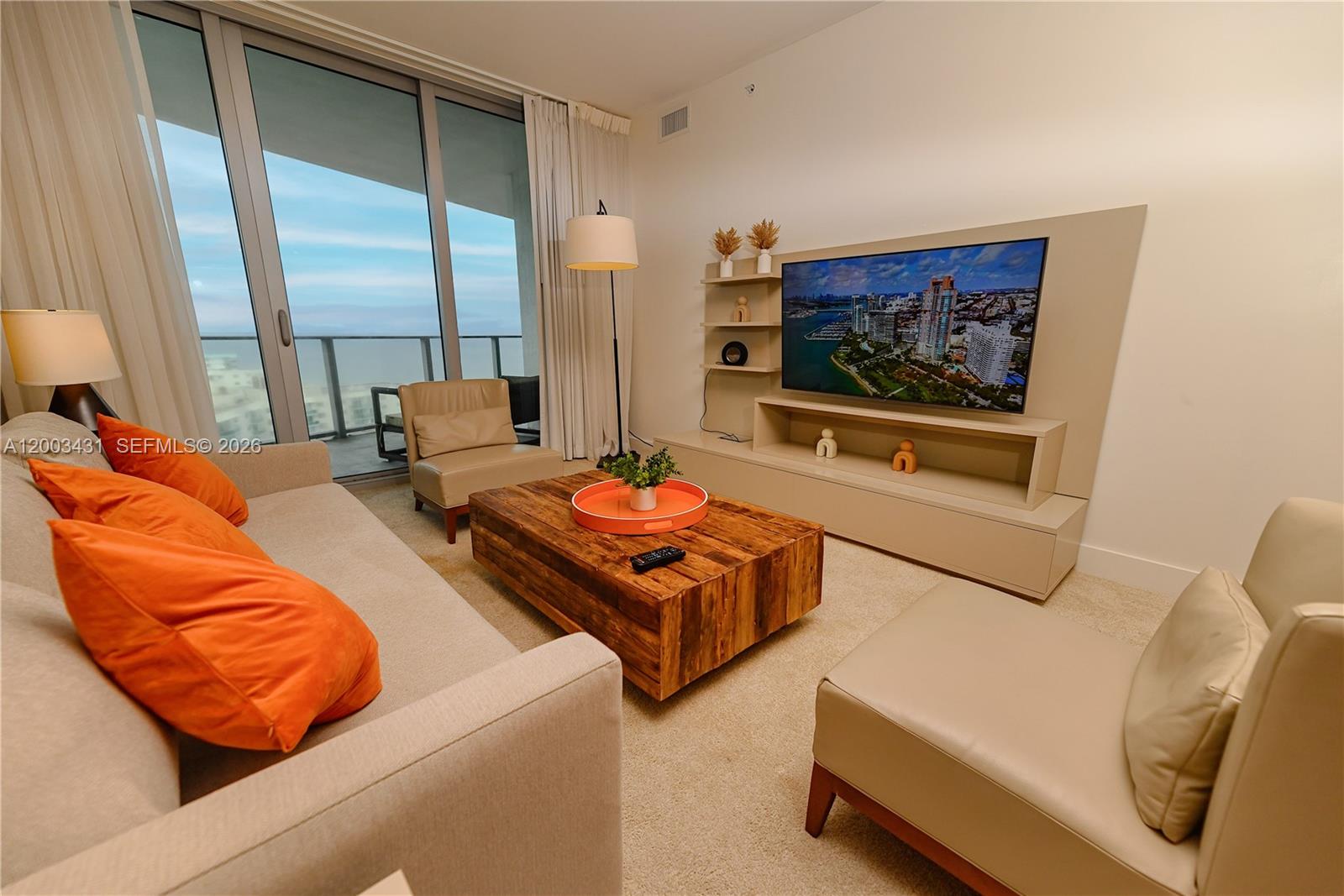 A living room features a beige sofa, wooden coffee table, and a wall-mounted television — 4111 S Ocean Dr # 1710, Hollywood FL 33019, HOLLYWOOD, FL