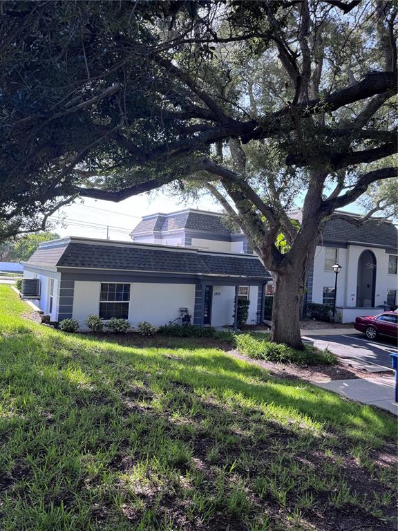 A low-rise apartment building with a gray roof and white exterior sits under large trees — 1201 N MCMULLEN BOOTH ROAD, CLEARWATER, FL