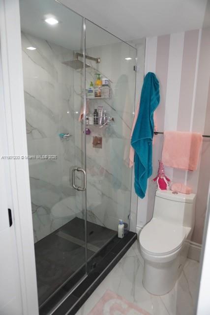 A bathroom features a glass-enclosed walk-in shower with marble-look tiles, a toilet, and striped wallpaper — 701 Brickell Key Blvd # 412, Miami FL 33131, MIAMI, FL
