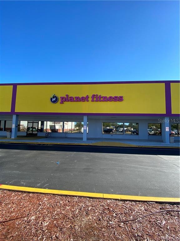 The exterior of a Planet Fitness gym features a yellow facade with purple trim — 1861 N HIGHLAND AVENUE, CLEARWATER, FL
