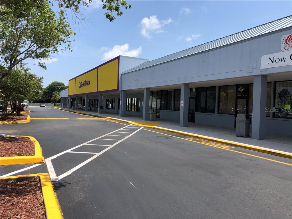 A view of a commercial strip mall with a yellow storefront and parking lot — 1861 N HIGHLAND AVENUE, CLEARWATER, FL