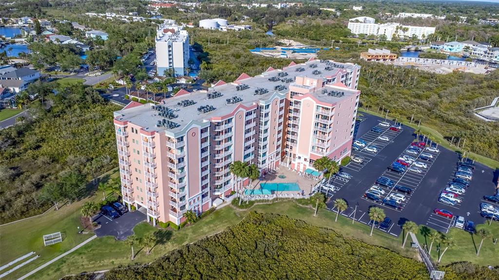 An aerial view shows a multi-story pink apartment building with a pool and parking lot — 4516 SEAGULL DRIVE UNIT 615, NEW PORT RICHEY, FL
