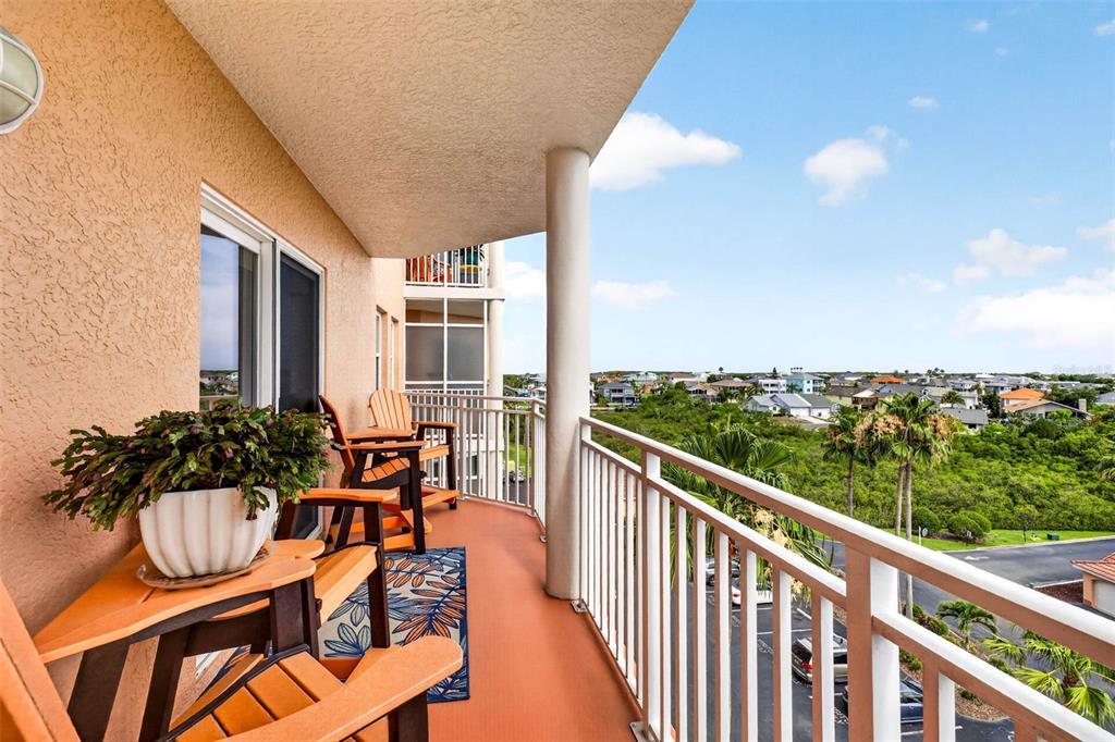 A balcony with orange flooring, wooden chairs, a potted plant, and a view of houses — 4516 SEAGULL DRIVE UNIT 615, NEW PORT RICHEY, FL