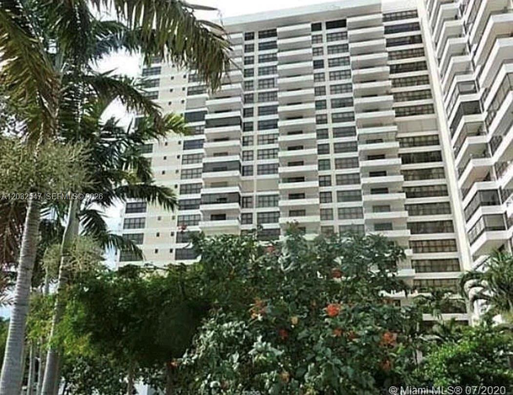A tall, white residential high-rise building is surrounded by lush green palm trees and foliage — 500 Three Islands Blvd # 314, Hallandale Beach FL 33009, HALLANDALE BEACH, FL