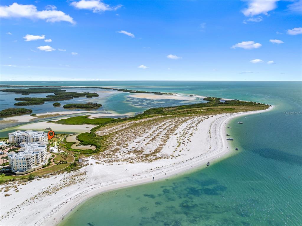An aerial view shows a coastal condominium complex situated next to a sandy beach — 795 COLLANY ROAD UNIT 204, TIERRA VERDE, FL