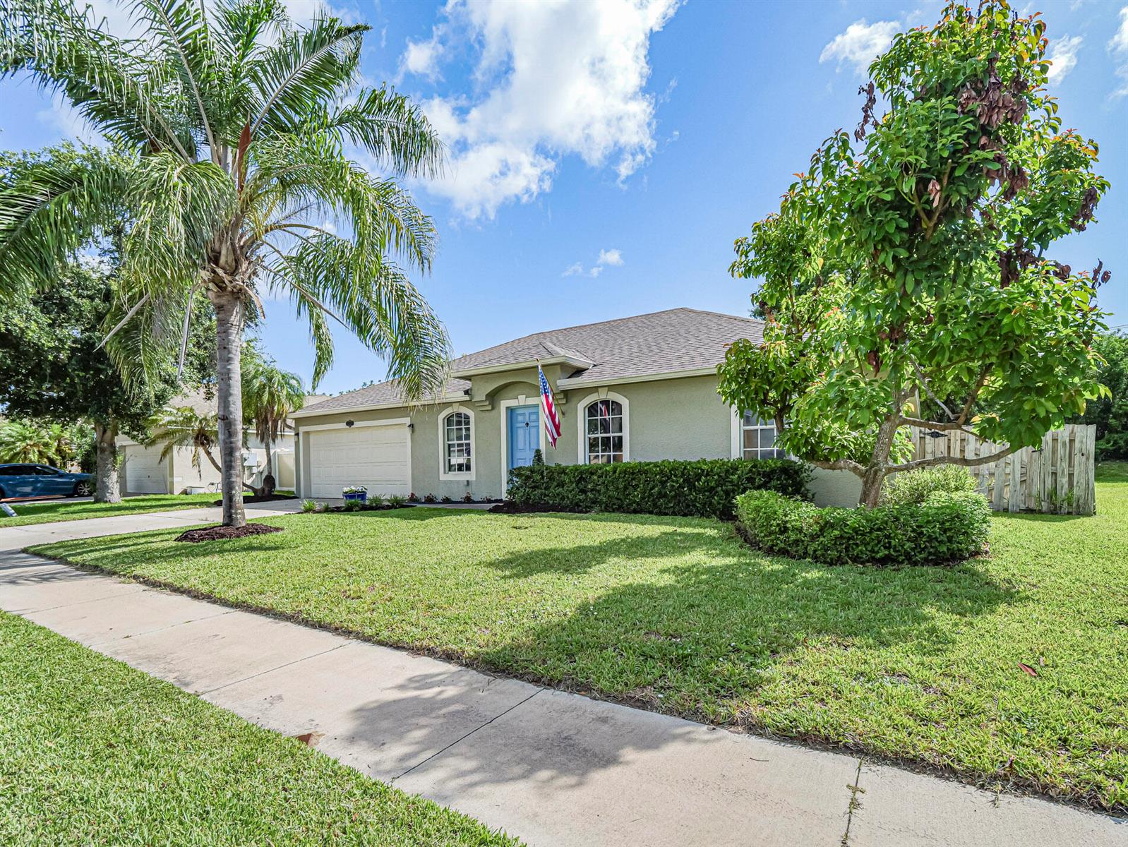 A single-story house with a light green exterior, a blue front door, and a palm tree — 6029 Ridge Lake Circle, Vero Beach FL 32967, VERO BEACH, FL