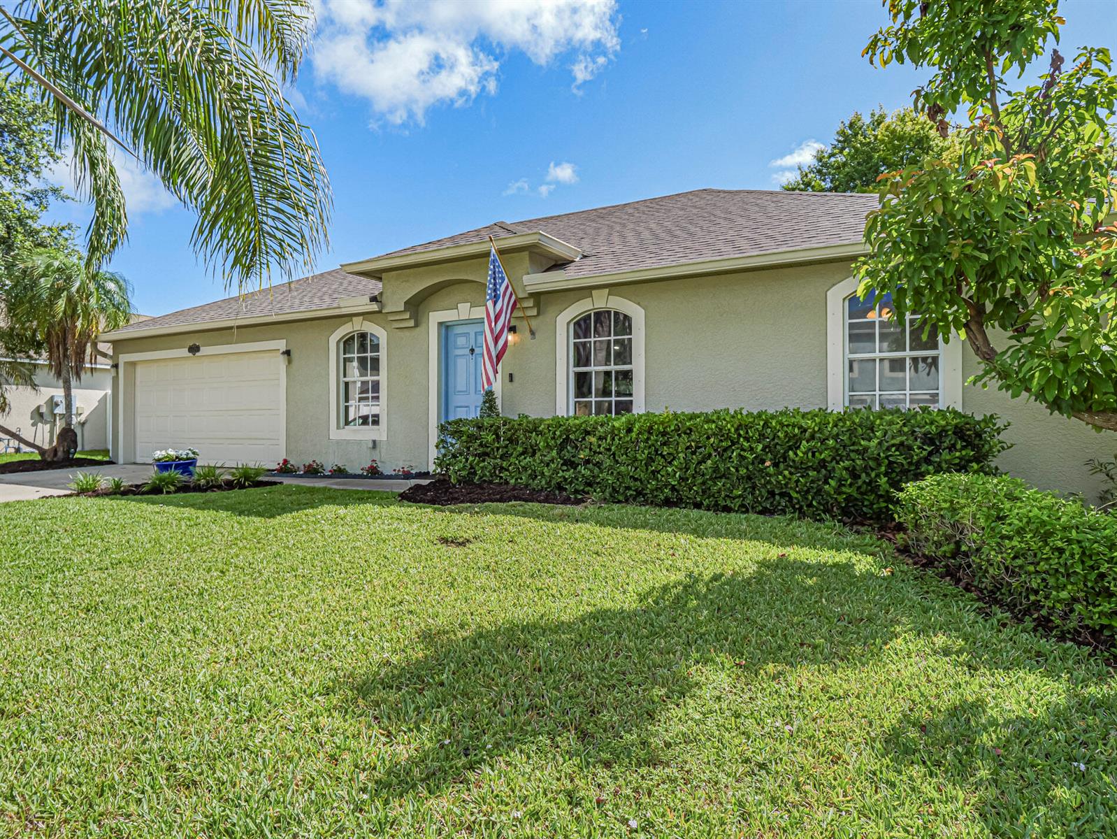 A single-story house with a light green exterior, a blue front door, and a manicured lawn — 6029 Ridge Lake Circle, Vero Beach FL 32967, VERO BEACH, FL