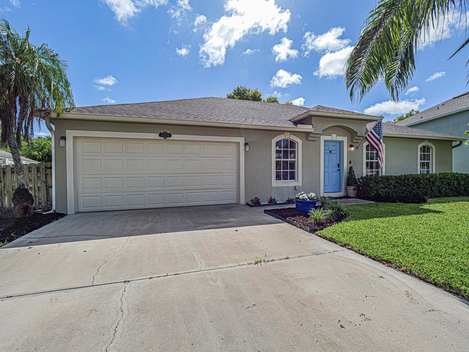 A single-story house with a beige stucco exterior, a two-car garage, and a blue door — 6029 Ridge Lake Circle, Vero Beach FL 32967, VERO BEACH, FL