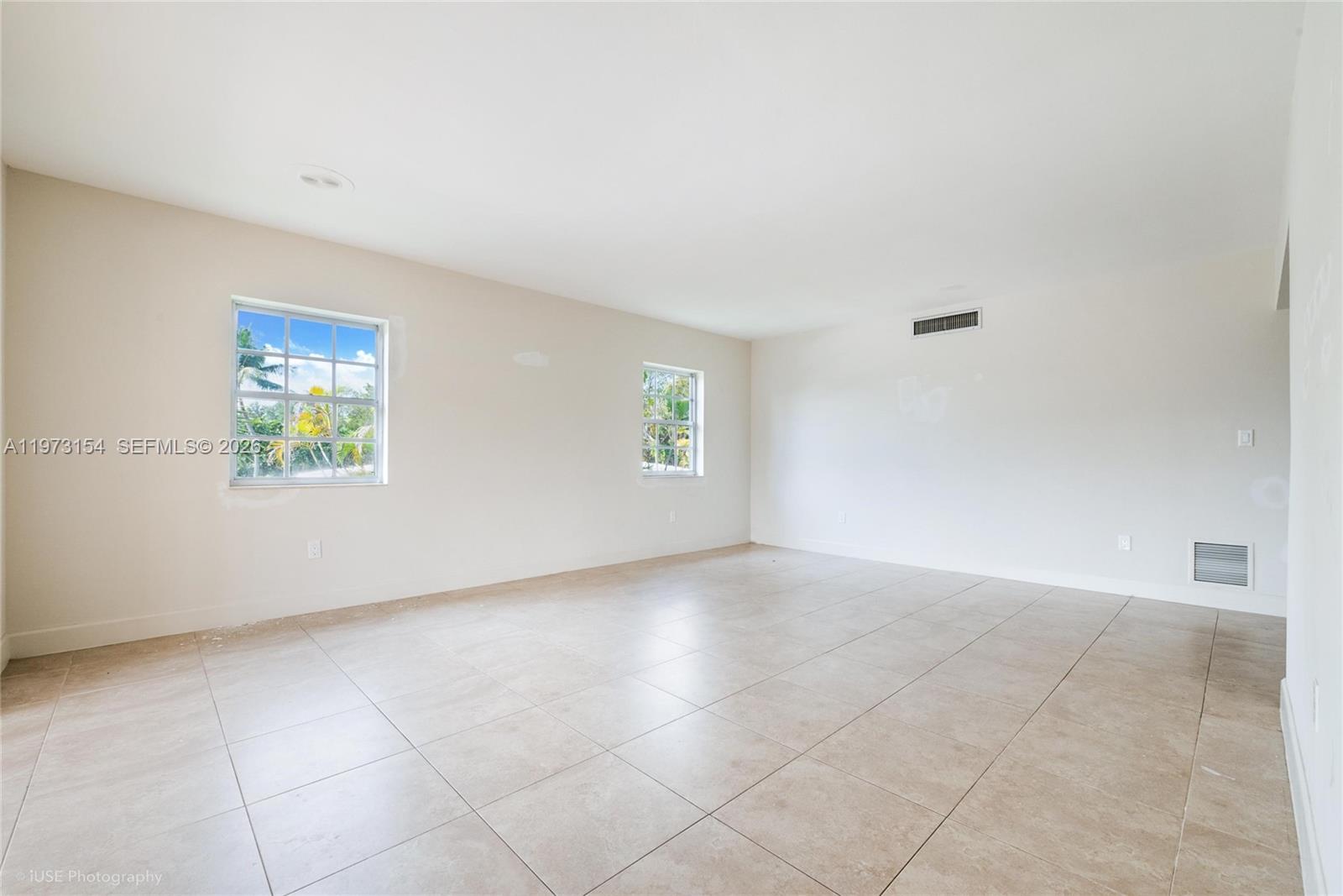 An empty room features beige tile flooring, white walls, and two windows — 1265 S Alhambra Cir # B, Coral Gables FL 33146, CORAL GABLES, FL