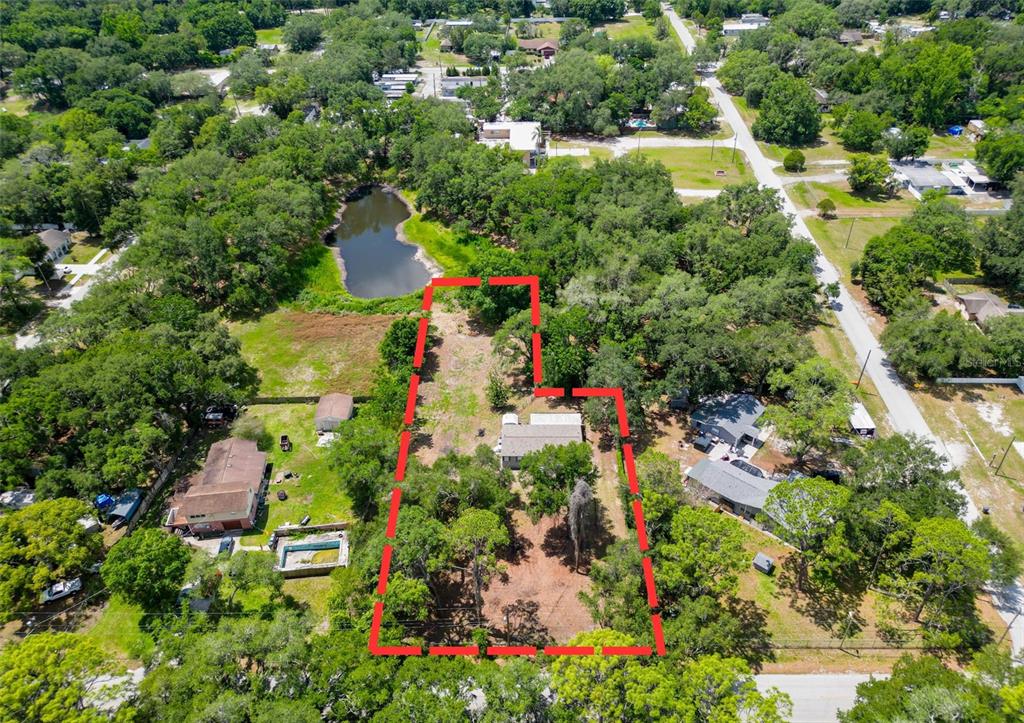 A single-story manufactured home sits on a grassy lot surrounded by mature trees at sunset — 1819 SINCLAIR HILLS ROAD, LUTZ, FL