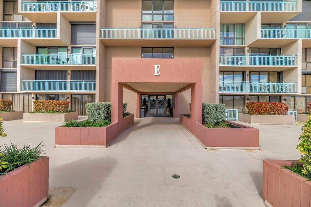 The exterior of a multi-story apartment building features a covered entrance marked with an E — 1 KEY CAPRI UNIT 209E, TREASURE ISLAND, FL
