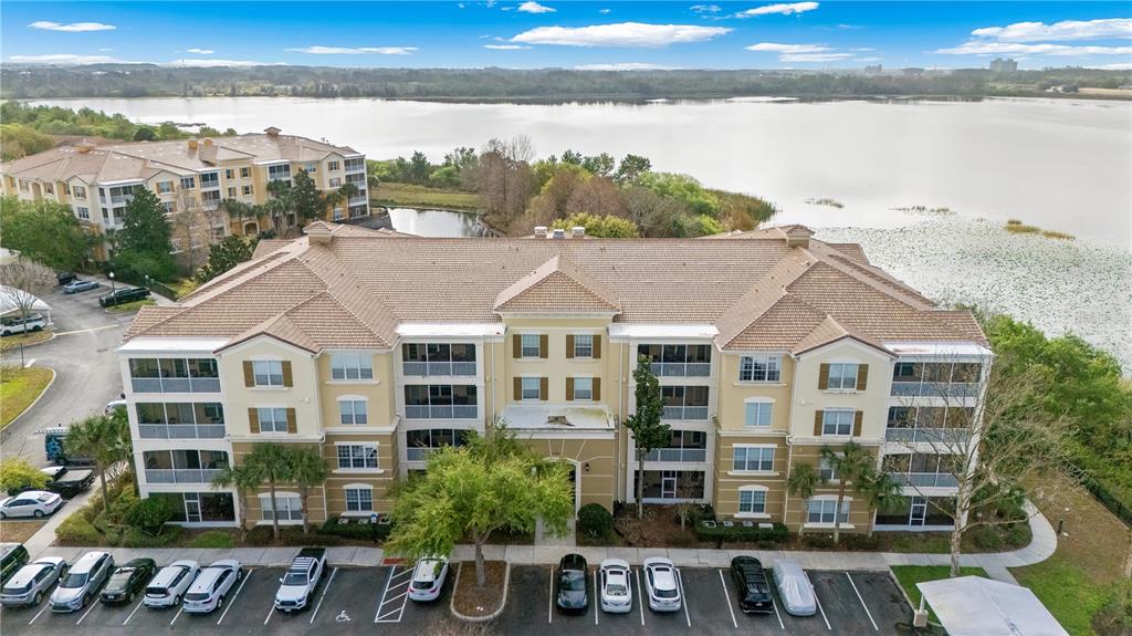 An aerial view shows a multi-story apartment building with a parking lot and lake — 3362 ROBERT TRENT JONES DRIVE UNIT 10407, ORLANDO, FL