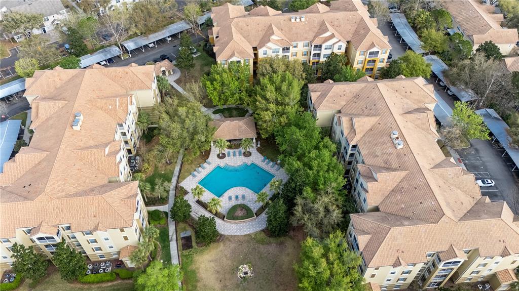 An aerial view shows apartment buildings surrounding a central swimming pool and patio area — 3362 ROBERT TRENT JONES DRIVE UNIT 10407, ORLANDO, FL