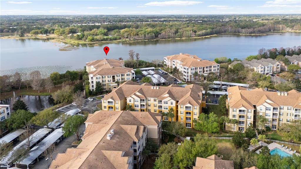 An aerial view shows several multi-story apartment buildings situated next to a large lake — 3362 ROBERT TRENT JONES DRIVE UNIT 10407, ORLANDO, FL
