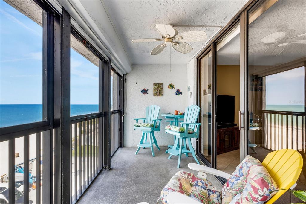 A screened-in balcony features a ceiling fan, light blue patio furniture, and ocean views — 14900 GULF BOULEVARD UNIT 410, MADEIRA BEACH, FL