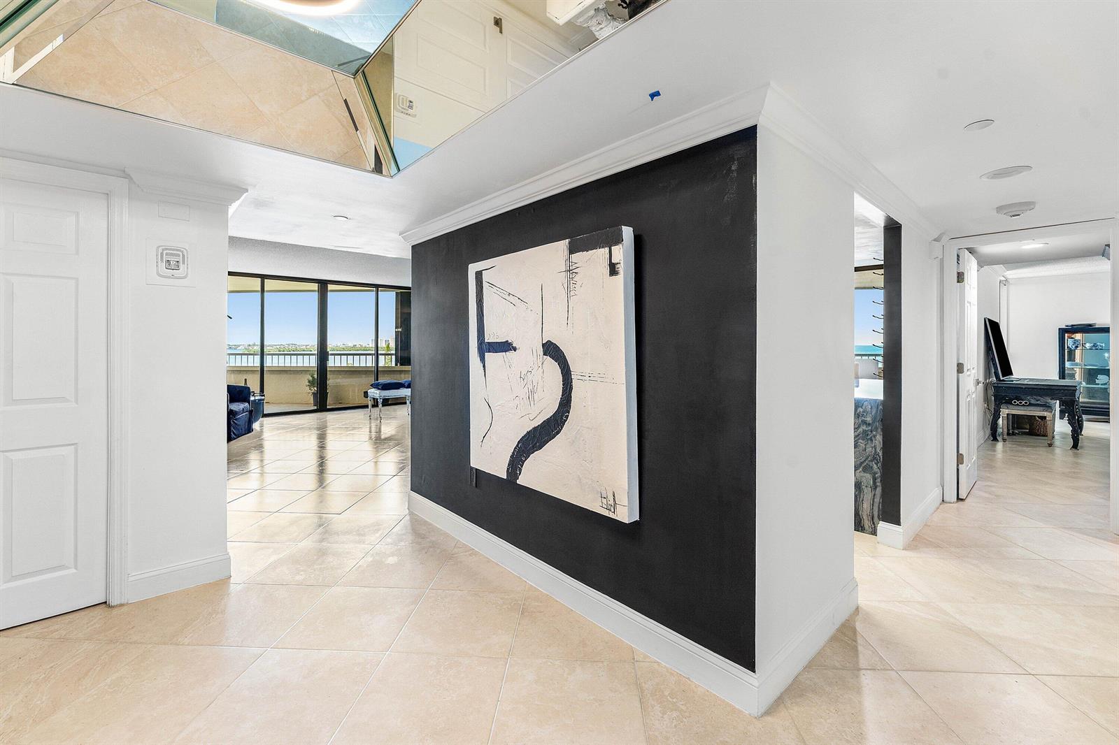 A hallway with beige tile floors features a black accent wall displaying abstract art — 5080 N Ocean Drive # 6b, Singer Island FL 33404, SINGER ISLAND, FL