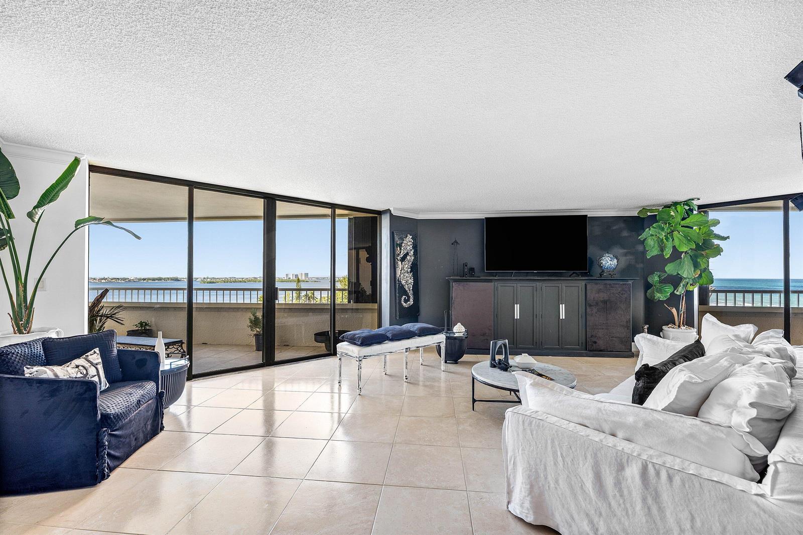 A living room with tile floors, a dark media console, and floor-to-ceiling windows overlooking water — 5080 N Ocean Drive # 6b, Singer Island FL 33404, SINGER ISLAND, FL